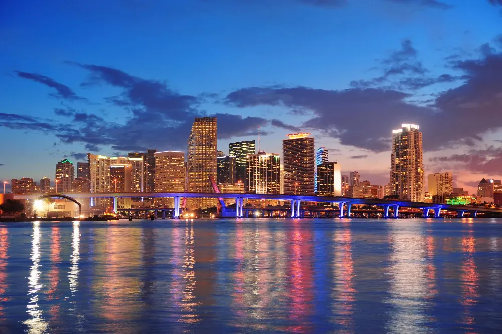 A downtown skyline reflected in the water at twilight