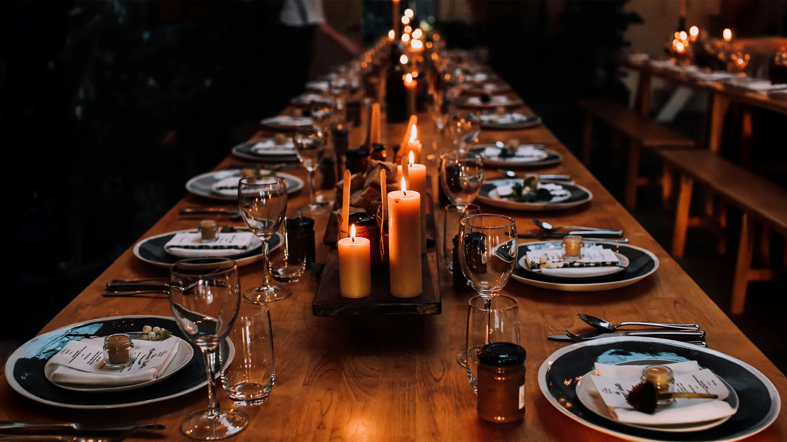 A long candlelit dinner table laid for an intimate executive gathering